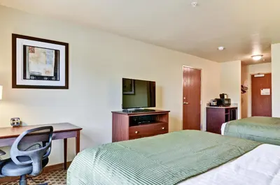 a hotel room with two beds and a desk and a television at Cobblestone Inn & Suites - Ambridge in Ambridge