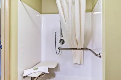 a white bathroom with a shower curtain and a toilet at Cobblestone Inn & Suites - Ambridge in Ambridge
