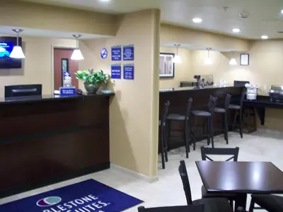a restaurant with a bar and tables and chairs at Cobblestone Inn & Suites - Ambridge in Ambridge