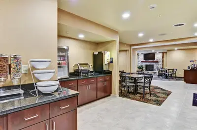 a large kitchen with wooden cabinets and a dining room at Cobblestone Inn & Suites - Ambridge in Ambridge
