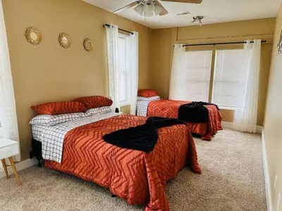 a bedroom with three beds with orange comforters at Tranquility in Trenton -Sleeps 9 in Trenton