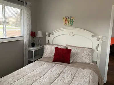 a bedroom with a white bed with a red pillow at 2 Homes for large group Hot Tub in Mason