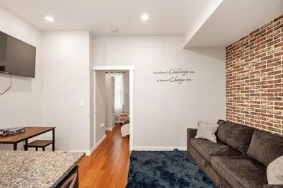 a living room with a couch and a brick wall at Sleep like a King - OTR- Free Light Rail ! in Cincinnati