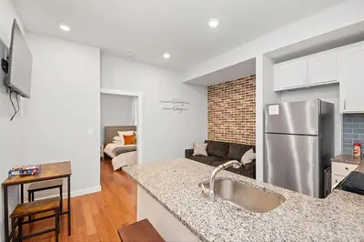 a kitchen with a refrigerator and a living room at Sleep like a King - OTR- Free Light Rail ! in Cincinnati