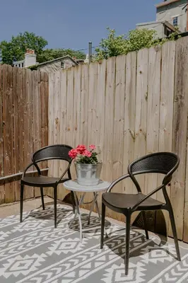two chairs and a table with flowers on a patio at Stunning 4BR Townhome Rooftop City Views in Cincinnati