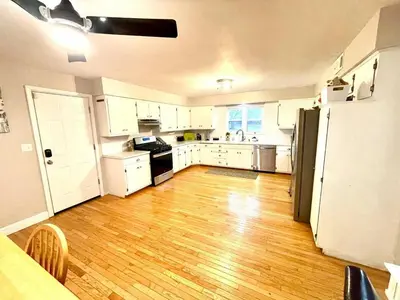 a kitchen with white cabinets and a wooden floor at Large Private Ranch - Master Bedroom Suite with King Bed and private Bathroom - Fenced Yard - Pets & Kids Welcome - Pool Table in Columbus