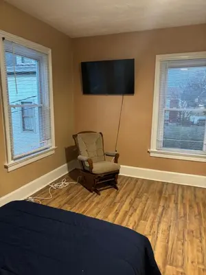 a bedroom with a chair and a television on the wall at Cozy Studio Private room in Cincinnati