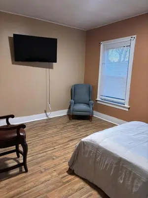 a bedroom with a bed and a chair and a television at Cozy Studio Private room in Cincinnati