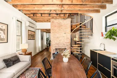 a living room with a wooden table and a brick fireplace at Luxury Loft near Washington Park - Rooftop Deck in Cincinnati