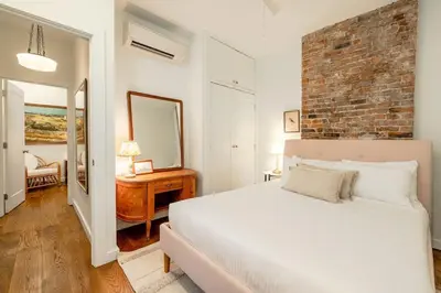 a bedroom with a white bed and a brick wall at Walk to ALL - Washington Park - Gorgeous 2BR Condo in Cincinnati