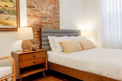 a bedroom with a bed and a brick wall at Walk to ALL - Washington Park - Gorgeous 2BR Condo in Cincinnati