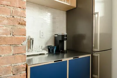 a kitchen with a refrigerator and a brick wall at Walk to ALL - Washington Park - Gorgeous 2BR Condo in Cincinnati