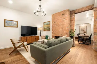 a living room with a couch and a brick wall at Walk to ALL - Washington Park - Gorgeous 2BR Condo in Cincinnati