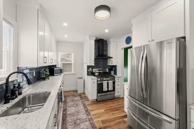 a kitchen with white cabinets and a stainless steel refrigerator at Hot Tub - Game Room - Chic & Spacious - Sleeps 10 in Cleveland