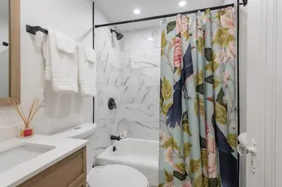 a bathroom with a shower curtain with a toilet and a sink at Hot Tub - Game Room - Chic & Spacious - Sleeps 10 in Cleveland