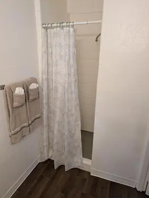 a shower with a white shower curtain in a bathroom at Terry Point Motel in Richfield