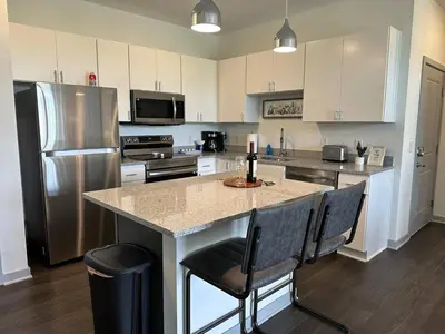 a kitchen with a large island with chairs and a refrigerator at The Dublin Designer 1st Floor Available Now in Dublin