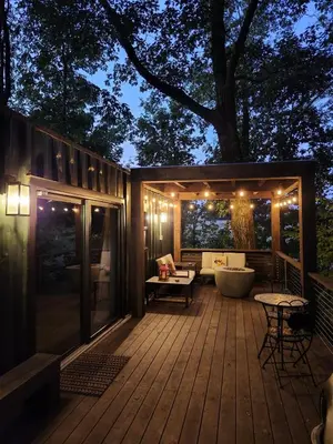 a deck with a tub and a tree at night at Wildwood Retreat in Dalton