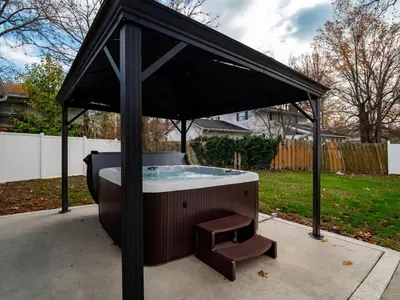 a hot tub with a bench under an umbrella at Vermilion Retreat with Game Room, Hot Tub and Across from Community Pool in Vermilion