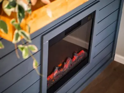 a fireplace in a blue cabinet with a fire inside at Vermilion Retreat with Game Room, Hot Tub and Across from Community Pool in Vermilion