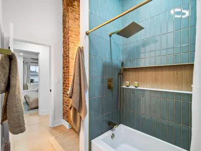 a bathroom with a tub and a shower with blue tiles at Luxurious Retreat with Sauna and Modern Design in Warrensville Heights