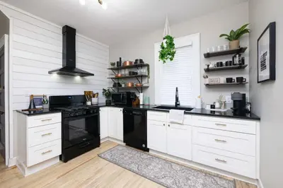 a kitchen with white cabinets and black appliances at Walk to Highland Square, Sleeps 8 in Akron