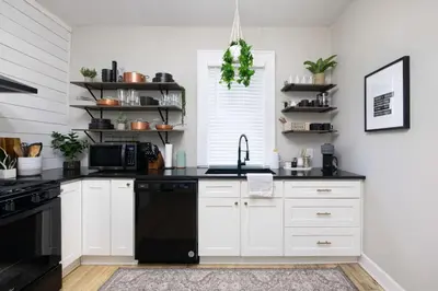 a kitchen with white cabinets and a black dishwasher at Walk to Highland Square, Sleeps 8 in Akron