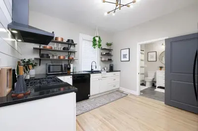 a kitchen with white cabinets and a black stove top oven at Walk to Highland Square, Sleeps 8 in Akron
