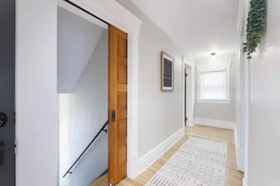 a hallway with white walls and a wooden door at Walk to Highland Square, Sleeps 8 in Akron