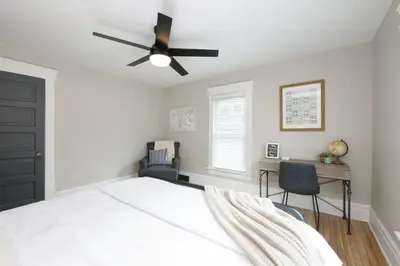 a bedroom with a bed with a ceiling fan and a desk at Walk to Highland Square, Sleeps 8 in Akron