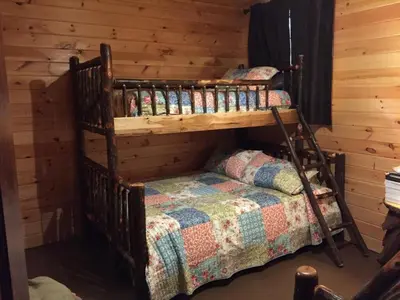 a bedroom with two bunk beds in a log cabin at The Secluded Woodbury Cabin, Pond and 42 acres in Warsaw