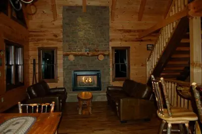 a living room with a fireplace in a log cabin at The Secluded Woodbury Cabin, Pond and 42 acres in Warsaw