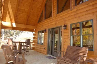 a wooden cabin with a table and chairs on a porch at The Secluded Woodbury Cabin, Pond and 42 acres in Warsaw