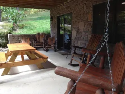 a porch with a swing and a table and chairs at The Secluded Woodbury Cabin, Pond and 42 acres in Warsaw