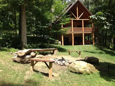 a log cabin with a picnic table and a fire pit at The Secluded Woodbury Cabin, Pond and 42 acres in Warsaw