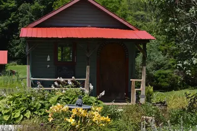 a small shed with a red roof in a garden at Mohican Farmhouse, Pond, and Animals in Perrysville