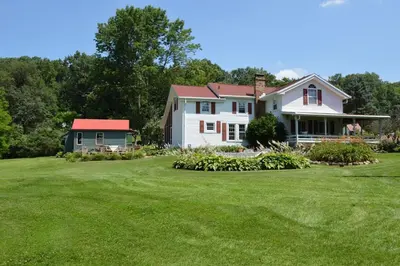 a white house with a red roof and a yard at Mohican Farmhouse, Pond, and Animals in Perrysville