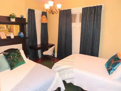 a bedroom with two beds and a window with curtains at The Nook on Neil Walkable 3BR in Columbus