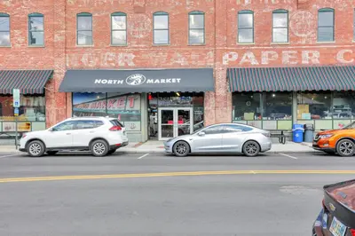 two cars parked in a parking lot in front of a store at The Nook on Neil Walkable 3BR in Columbus