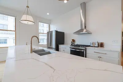 a white kitchen with a sink and a refrigerator at 'Condo A' Gallery Suite - Downtown Marion in Warren