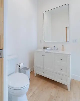 a white bathroom with a toilet and a mirror at 'Condo A' Gallery Suite - Downtown Marion in Warren
