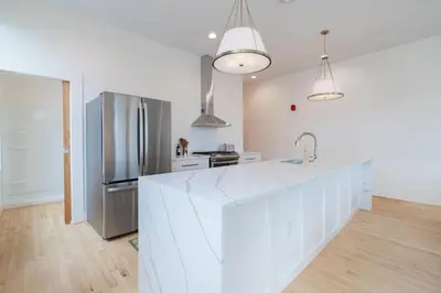 a white kitchen with a large white counter top at 'Condo A' Gallery Suite - Downtown Marion in Warren