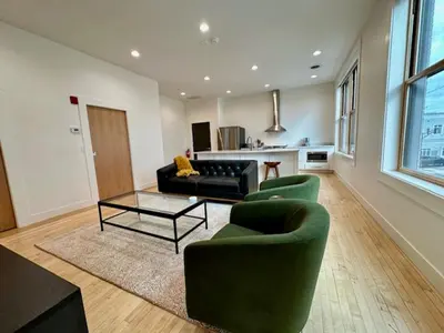 a living room with two green chairs and a table at Condo C - Gallery Suites Downtown Marion in Warren