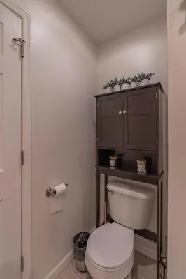a bathroom with a toilet and a wooden cabinet at Loft on Landess in Marion