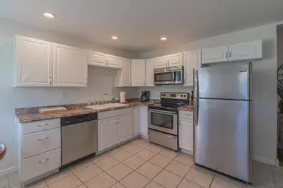 a kitchen with white cabinets and a stainless steel refrigerator at Loft on Landess in Marion