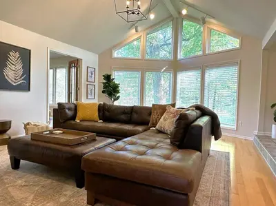 a living room with a brown leather couch and windows at Four Oaks Ranch in Marion