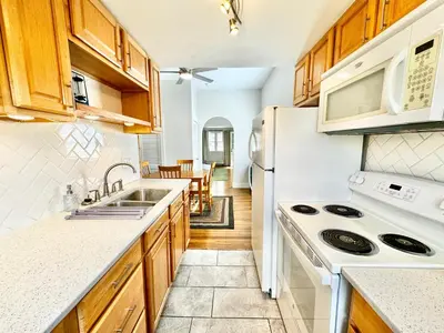 a kitchen with white appliances and wooden cabinets at Trojan Hideaway on First Street in Gas City