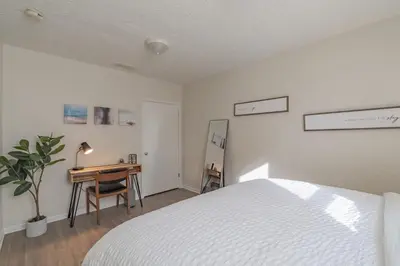 a white bedroom with a bed and a desk at University Suite 