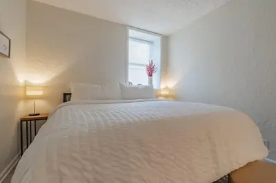a white bed in a room with a window at University Suite 