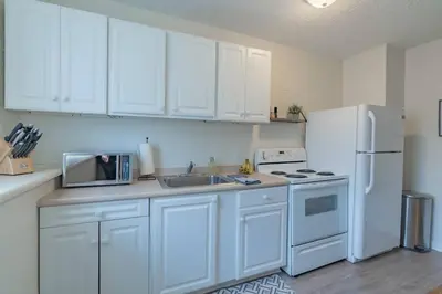 a kitchen with white cabinets and a white refrigerator at University Suite 